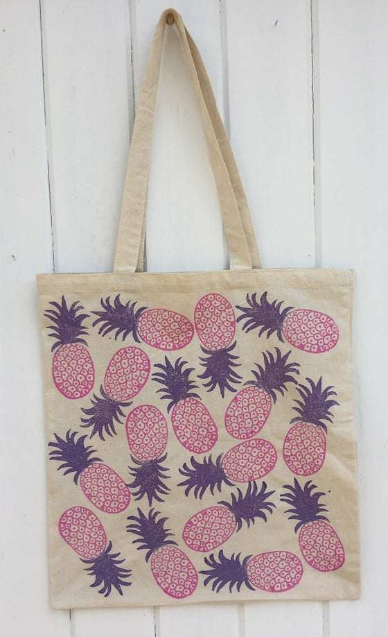 A hand block printed tote bag in a pink pineapple design
