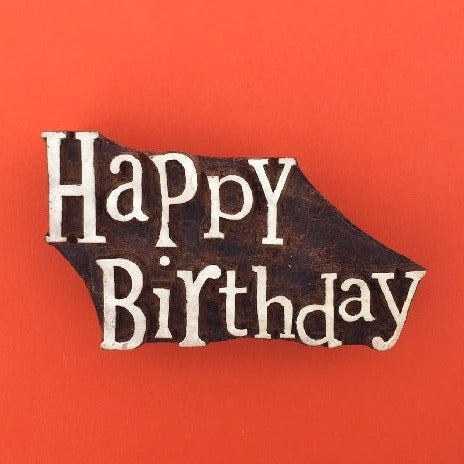 A hand carved Indian wooden printing block in a Happy Birthday text design, for printing cards, tags and wrapping paper