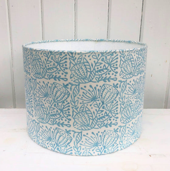A hand block printed lampshade printed in a duck egg blue seed head design