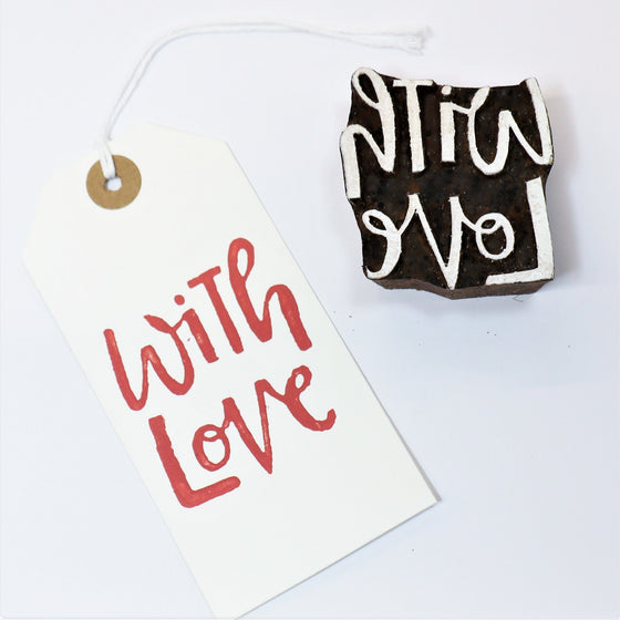 A hand carved Indian wooden printing block in a 'with love' text design